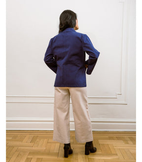 A model shows the backside of a blue chore jacket with front pockets and wide sleeves. The Angelica Jacket in Twilight is designed from Loup and made in New York City, USA.