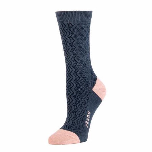 Navy blue knitted sock with dark blue crisscrossed pattern. Heel and toe of sock are light pink as well as the logo along the arch. The Aran Knit in Indigo is from Zkano and made in Alabama, USA.