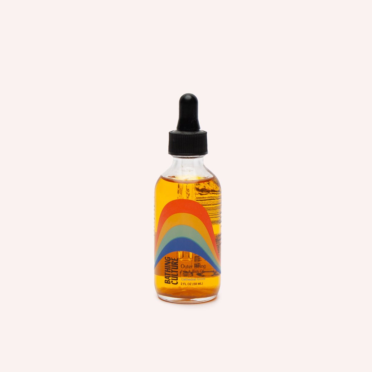 A clear glass bottle with a black dropper top holds a face and body oil. The Outer Being Face & Body oil is handcrafted by Bathing Culture in San Francisco, California.