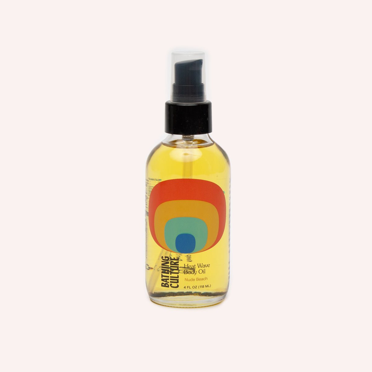 A clear bottle with a black pump top holds a body oil. The Heat Wave Body Oil is handcrafted by Bathing Culture in San Francisco, California.