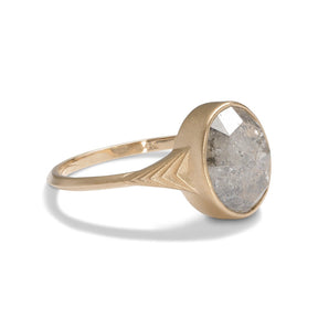 Modern oval Nubis ring with a salt & pepper diamond. 14K gold band features geometric engravings.