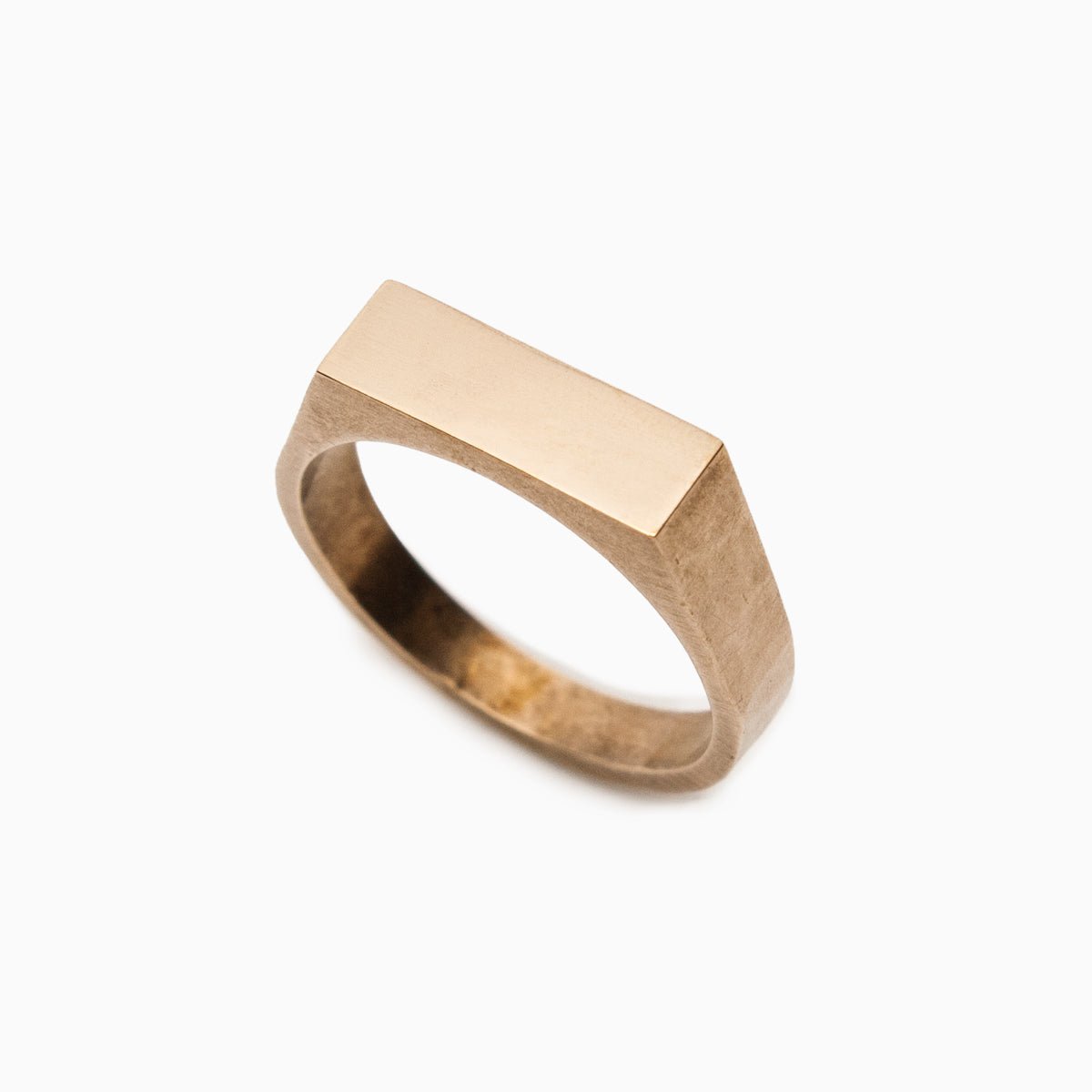 A narrow signet ring with a polished rectangular top and hammered detail on the band. Made in bronze. Designed and handcrafted in Portland, Oregon.
