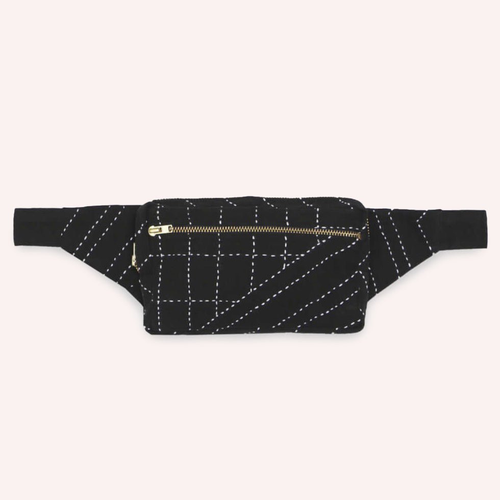 A black crossbody bag with white stitched detail. The Crossbody Belt Bag in Charcoal is designed by Anchal in Louisville, KY and handmade in Ajmer, India.