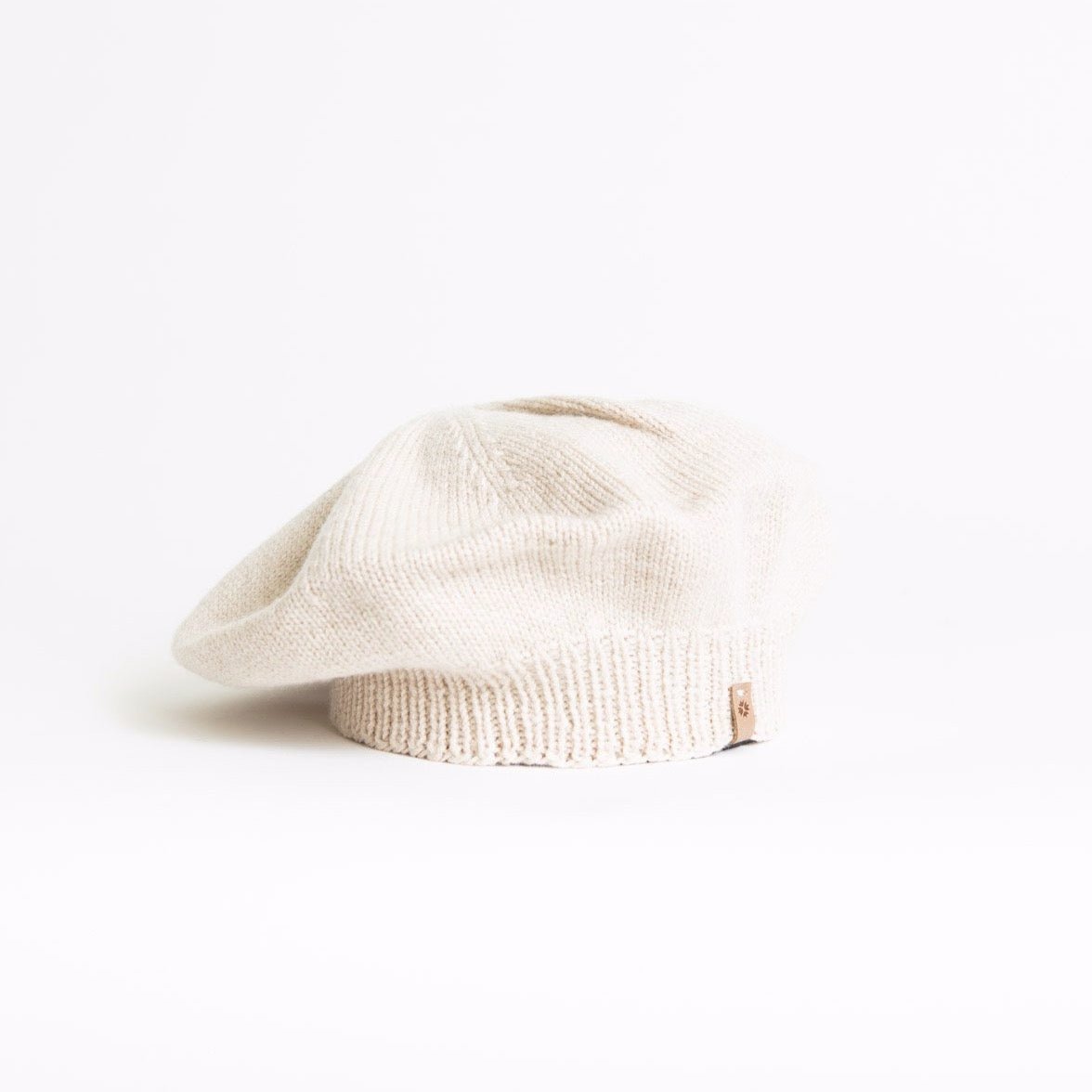 A slouch style hat with fitted ribbed collar. The Merino Beret in Almond White is designed by Dinadi and hand knitted in Kathmandu, Nepal.