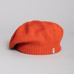 A slouch style hat with a fitted ribbed collar. The Merino Beret in Burnt Orange is designed by Dinadi and hand knitted in Kathmandu, Nepal.