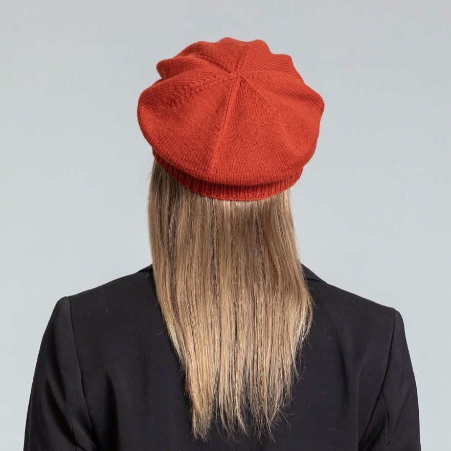 Model shows the back side of a slouch style hat with a fitted ribbed collar. The Merino Beret in Burnt orange is designed by Dinadi and hand knitted in Kathmandu, Nepal.
