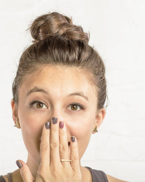 A model holds her hand up to her mouth showing off the betsy & iya gold and silver minimalist badlands ring.
