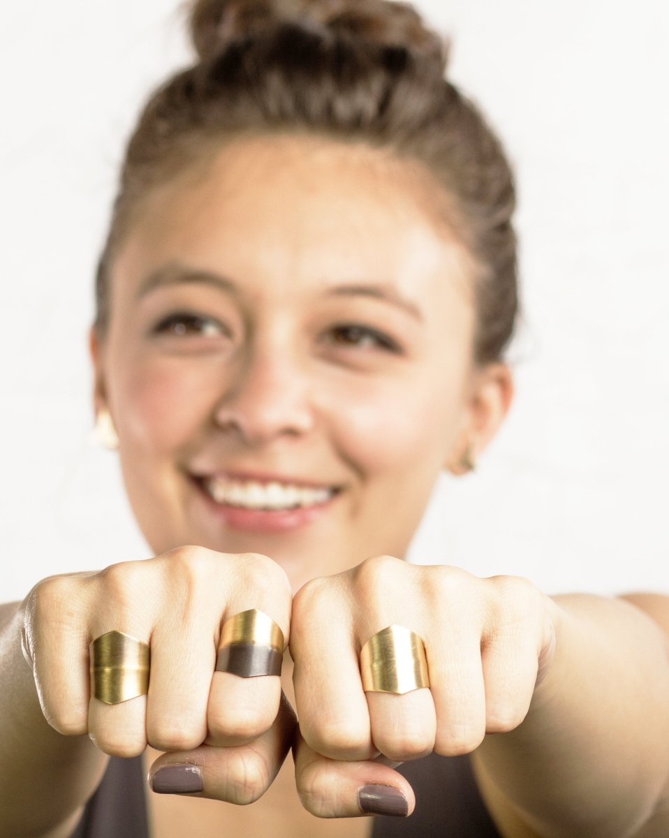 A woman holds hands up to camera, modeling different versions of the betsy & iya night watch wide band ring.