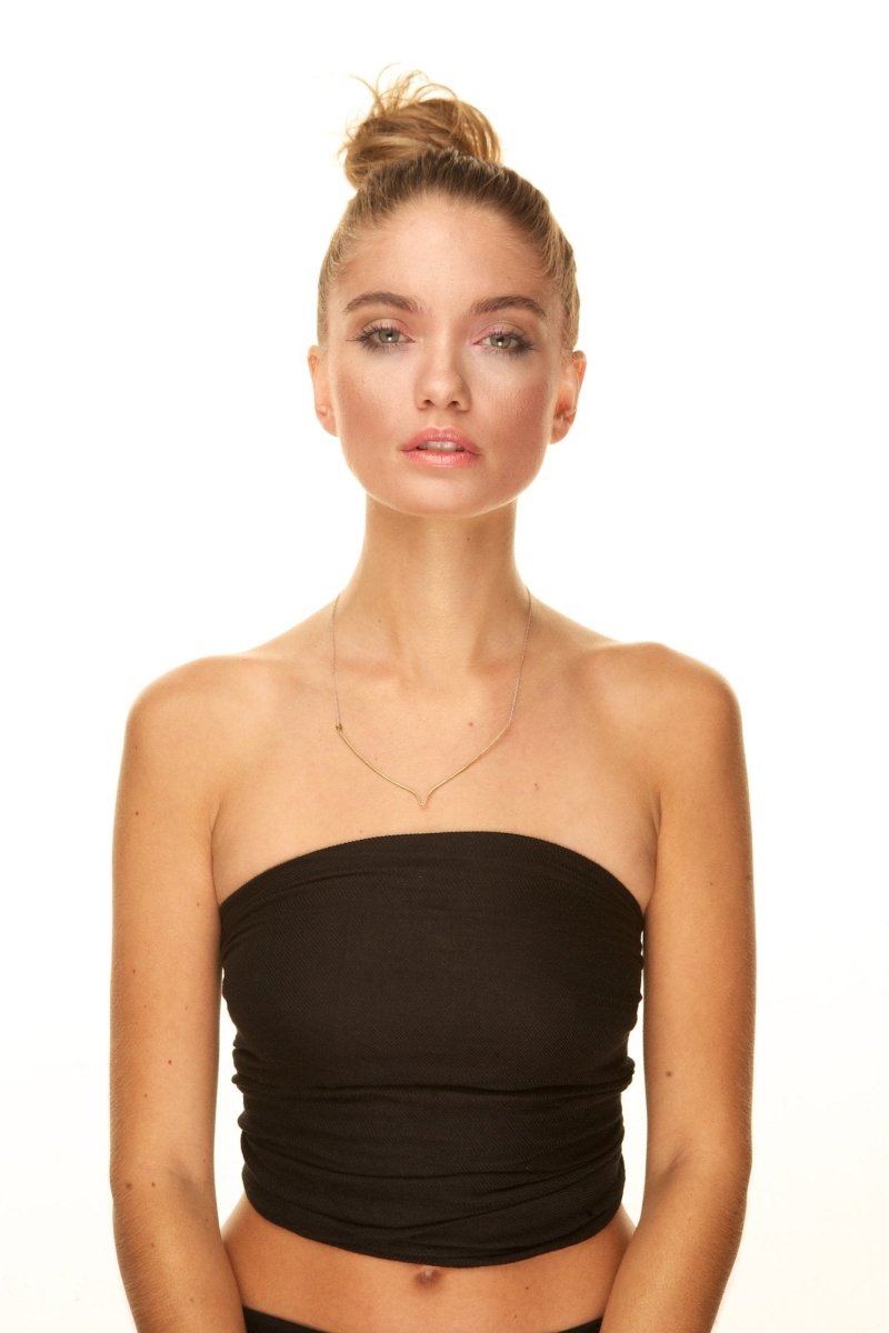 A model wears a long gold and black deco inspired necklace made by betsy and iya.