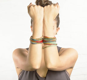 Model holds up both arms in front of her face, displaying how multiple betsy & iya colorful leather bracelets can be worn at once.
