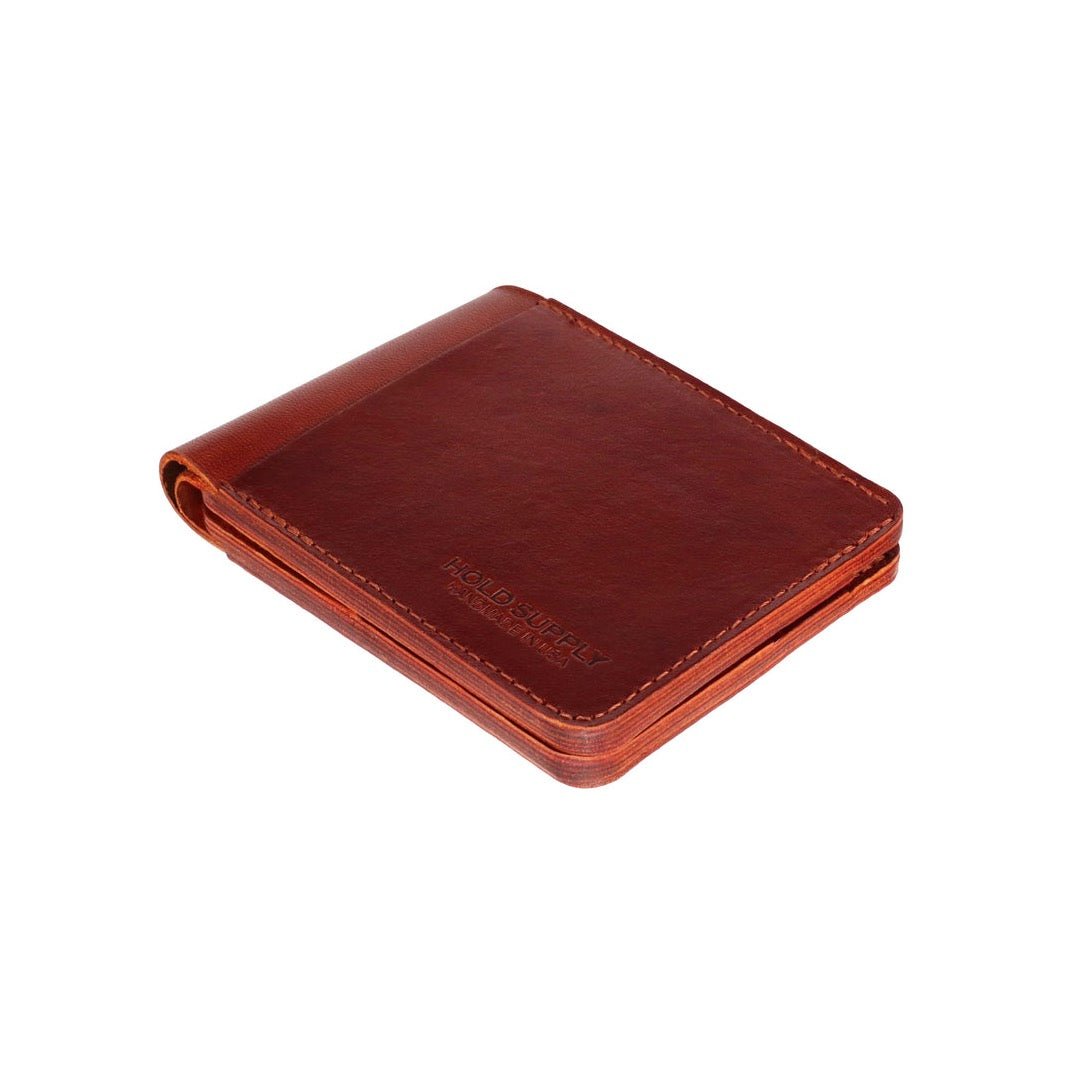 A folded over brown leather bi-fold wallet. The Leather Bi-Fold Wallet in Brown is designed and handcrafted by Hold Supply in Anaheim, California.