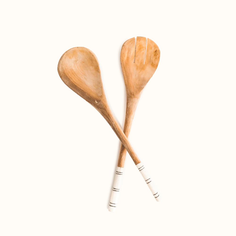 A hand-carved wooden serving set accented with cow bone handles. The Wooden Spoon Serving Set with Striped Handles is designed by Creative Women and hand-carved in Kenya.