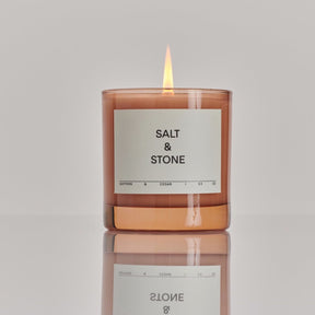 Light pink glass jar filled with a coconut and soy wax candle. The Saffron & Cedar Candle is designed by Salt & Stone and made in Los Angeles, CA