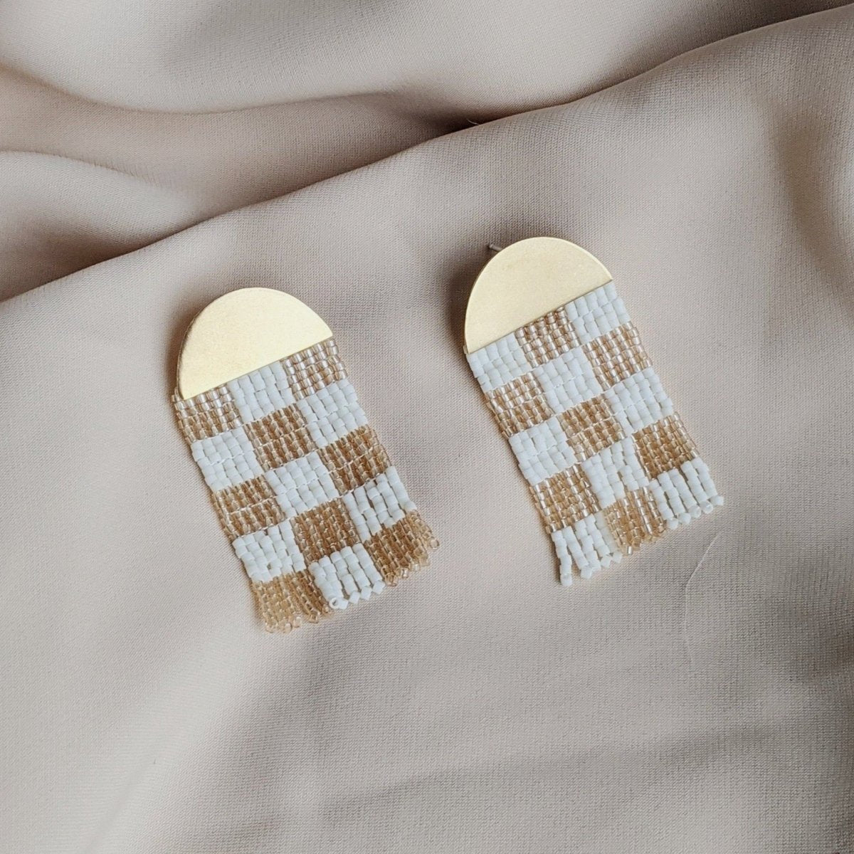 Champagne and white checkerboard patterned woven beaded earrings with a brass half circle. Designed and handmade by Take Shape Studio in Berkeley, California.