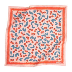 A light pink bandana with bright red and blue cherry illustrations and a solid red border. Designed by Hemlock Goods in Fulton, MO and screen printed by hand in India.