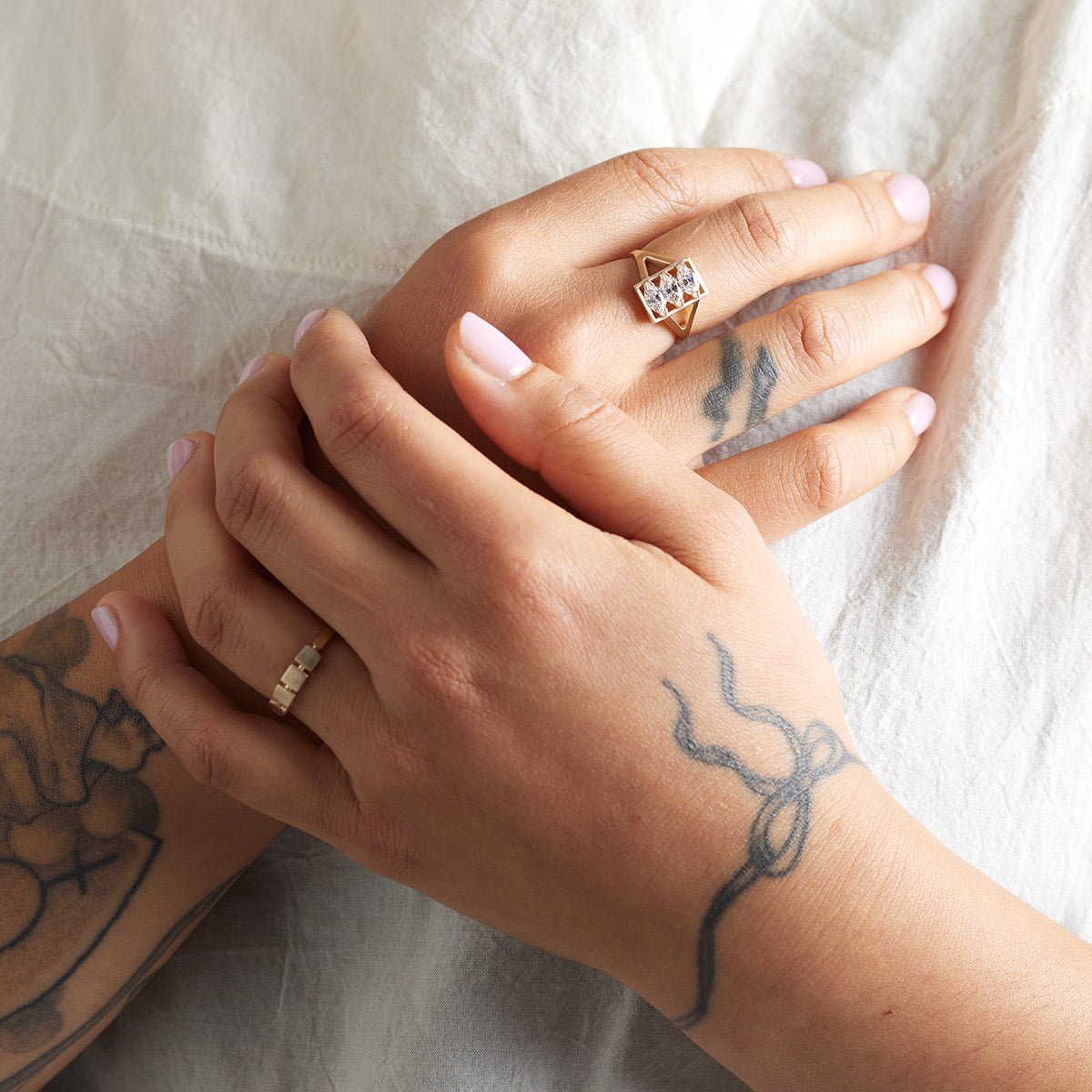 Model wears the Claro ring on their right hand and the Figura ring on their left hand.