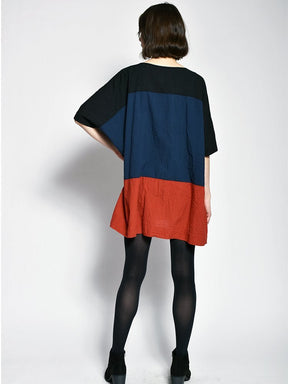 Model shows backside of a black, blue and red tunic style dress. The colorblock dress is designed and sewn by Uzi in Brooklyn, New York.