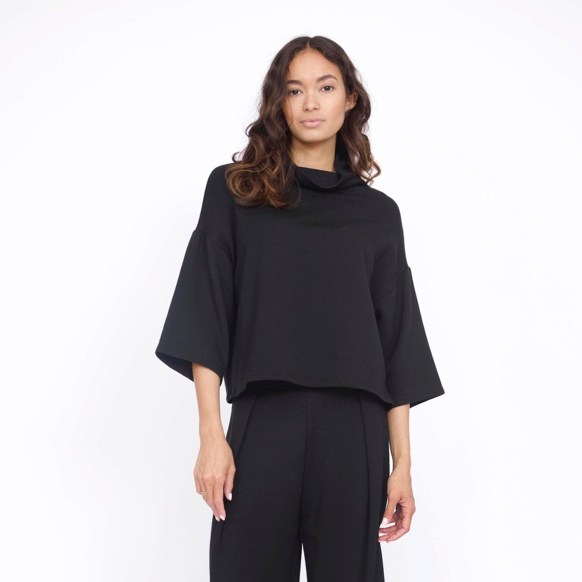 Loose fitting top with 3/4 sleeve and draped neck. The Bucket Sweater in Black is designed by Corinne and made in Los Angeles, CA.