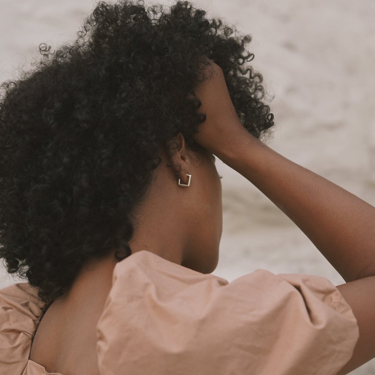A model wears a smooth silver tone square hoop earring with sterling silver earrings posts. The Courtyard Hoops are designed and handcrafted by Natalie Joy in Portland, Oregon.