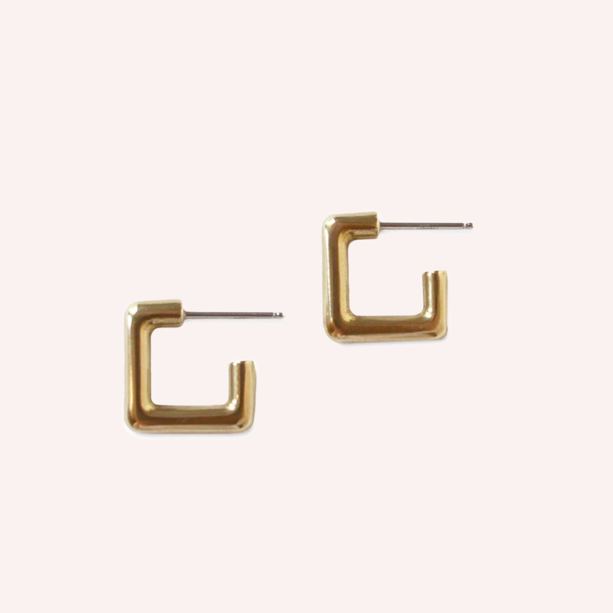 A smooth gold tone square hoop earring with sterling silver earrings posts. The Courtyard Hoops in Brass are designed and handcrafted by Natalie Joy in Portland, Oregon.