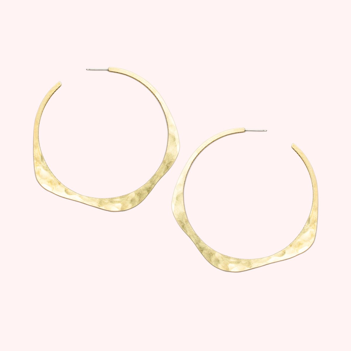 A brass hoop earring in a wave design with a hand hammered texture and sterling silver earring posts. The large Doble Hoop Earrings are designed and handcrafted in Portland, Oregon.