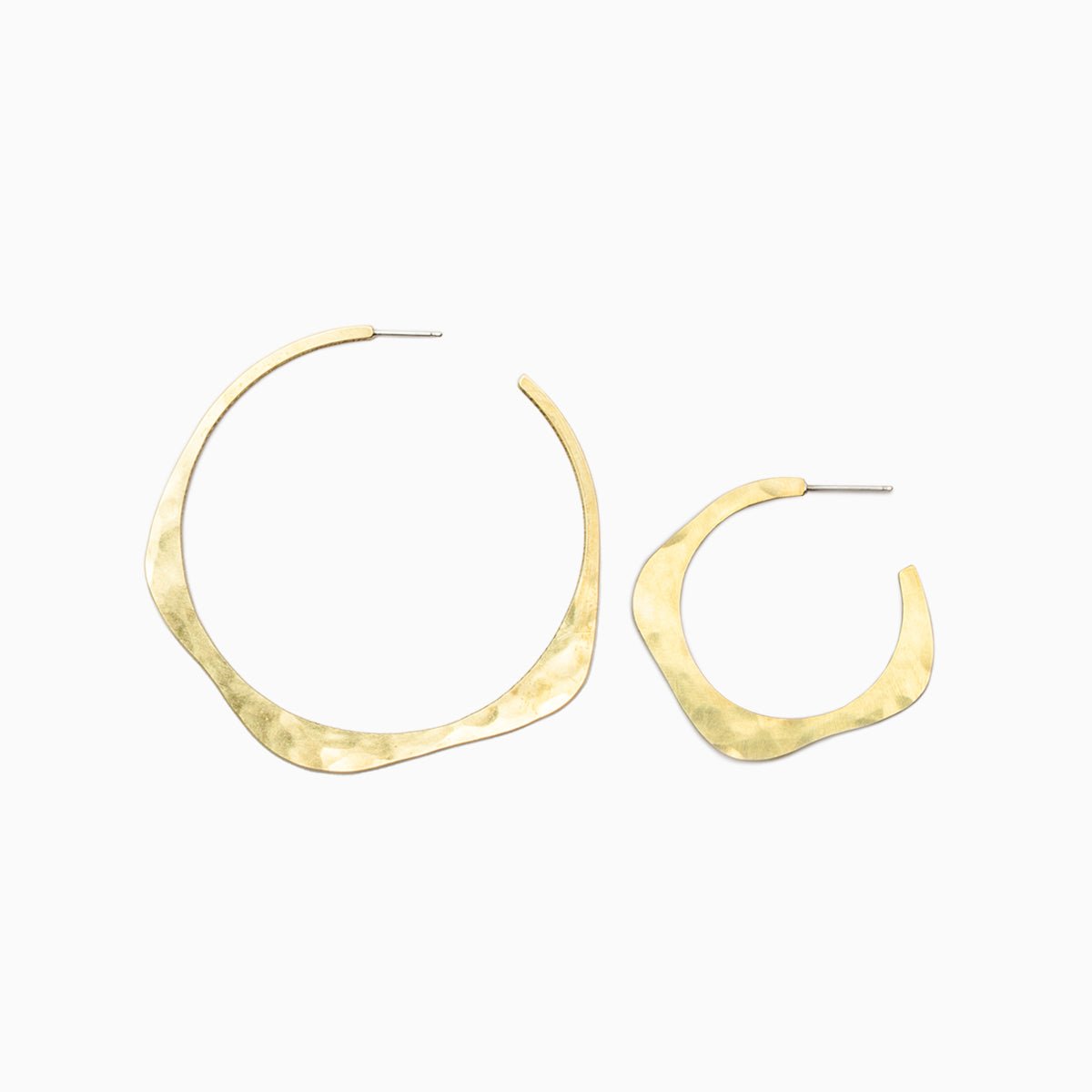The left earring is the large version of the brass Doble Hoop Earrings. The right earring is a small version of the Doble Hoop Earrings. Each earring is designed in a wave pattern and features hand hammered texture. The Doble Hoop Earrings are designed and handcrafted in Portland, Oregon.