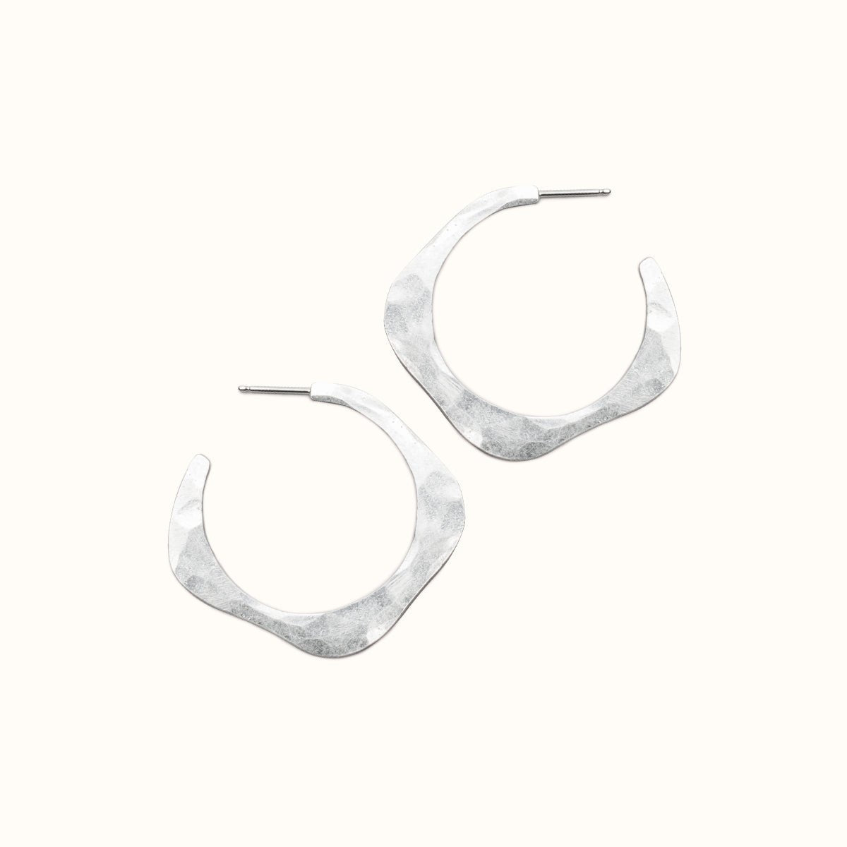A sterling silver hoop earring in a wave design with a hand hammered texture and sterling silver earring posts. The small Doble Hoop Earrings are designed and handcrafted in Portland, Oregon.