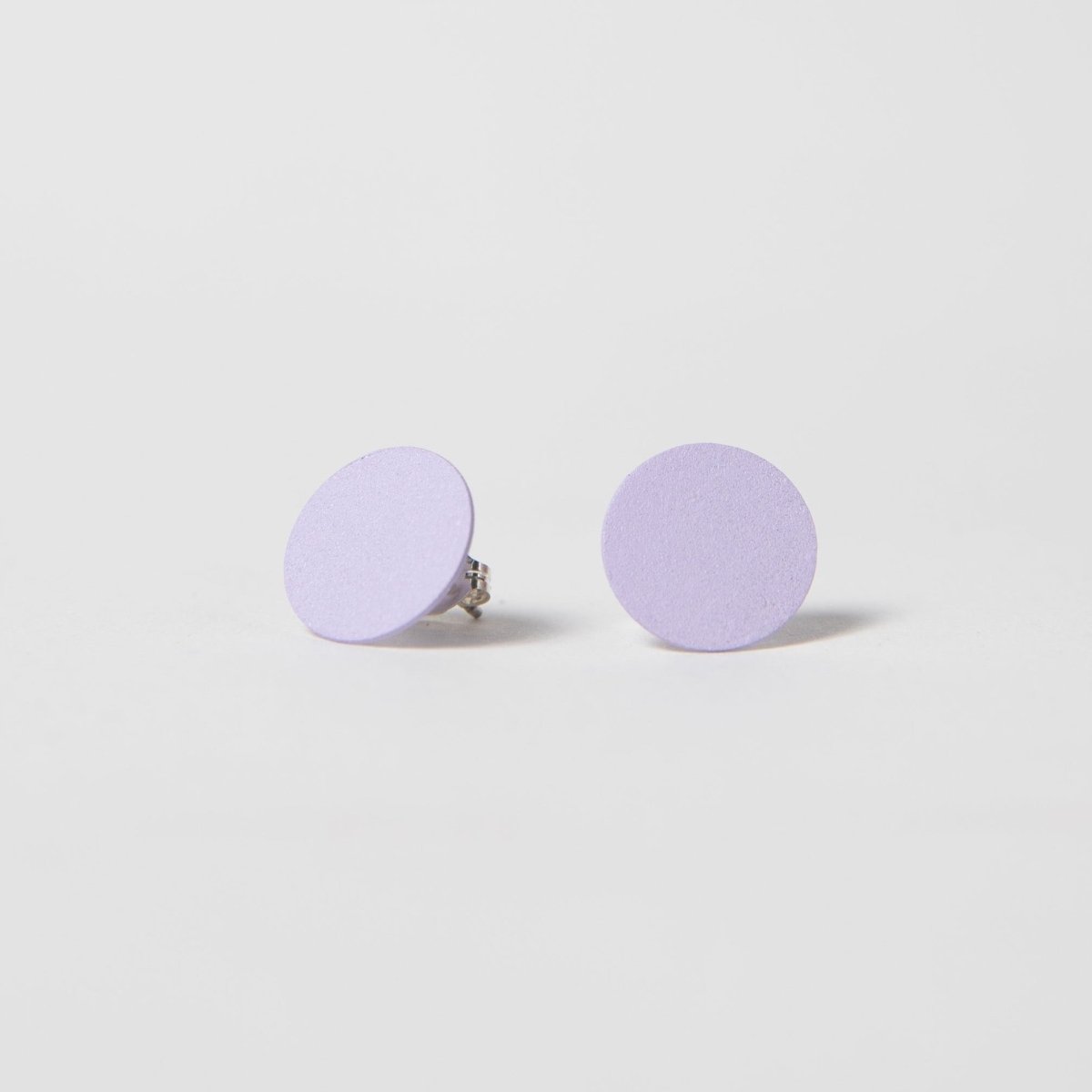 A round flat stud earring in pale purple. The Dot Earrings in Lilac are designed and crafted by Pretti.cool in Houston, Texas