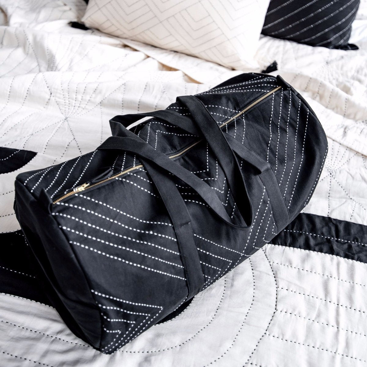 Black duffel bag with white stitched geometric design. Designed by Anchal in Louisville, Kentucky and made in Ajmer, India.