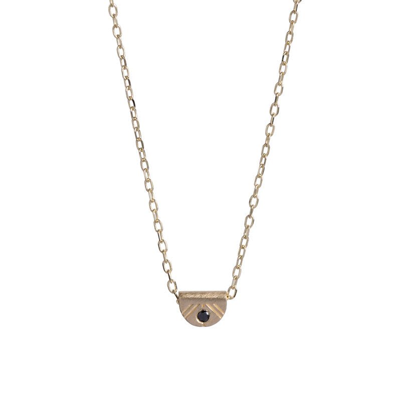 Tiny, half-moon pendant of 14k yellow gold, inlaid with a black diamond, and affixed to a delicate gold chain. Hand-crafted in Portland, Oregon.
