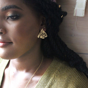 A model wears a textured 22kt gold plated stud earring in a fan shape with cutouts. The Edge of the Earth earrings are designed and handcrafted by Lingua Nigra in Chicago, Illinois.