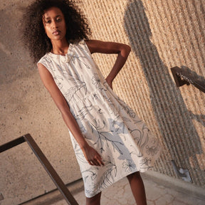 A white sleeveless dress with a route neckline and black line illustrations. The Galatee Dress in Cream & Black is designed and made by Eve Gravel in Montreal, Canada. 