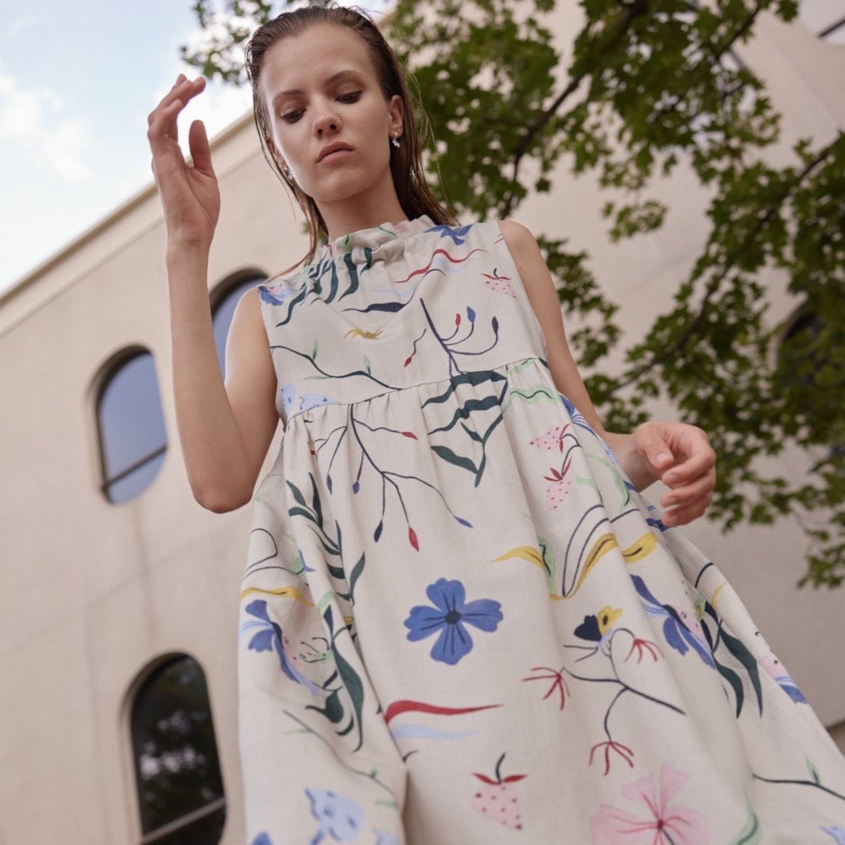 A sleeveless dress with a rouche neckline adorned with blue, yellow, green, pink and red garden illustrations. The Gale Dress in Color is designed and made by Eve Gravel in Montreal, Canada.