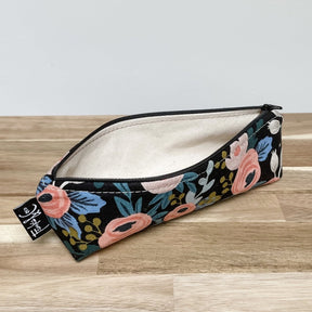 Narrow black canvas pencil case with pink, blue, white and green floral design. The Grant Pencil Case in Dark Roses is designed and handmade by Frankie & Coco in Portland, OR.