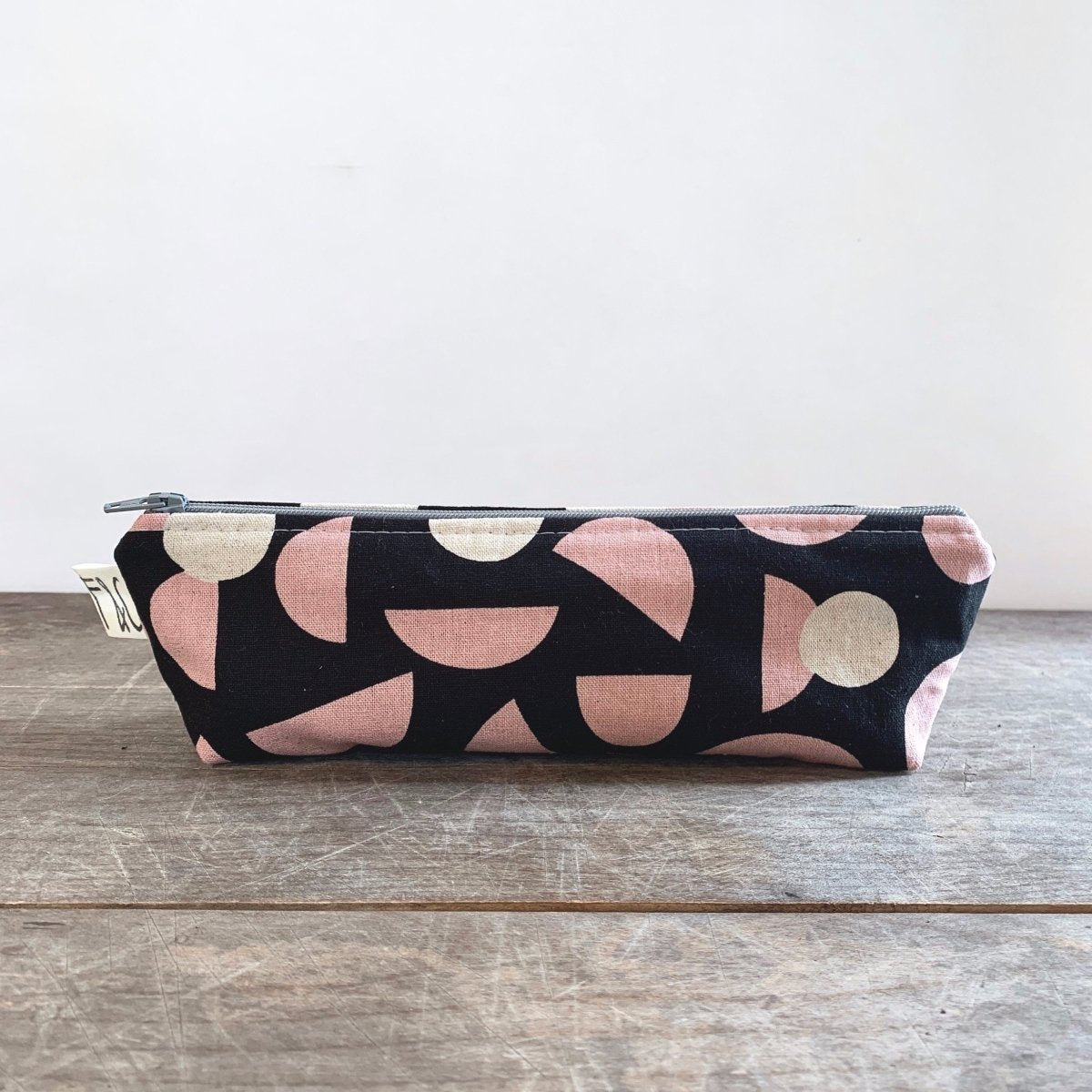 Narrow black canvas pencil case with pink and cream colored concentric shapes. Designed and handmade by Frankie & Coco in Portland, Oregon.
