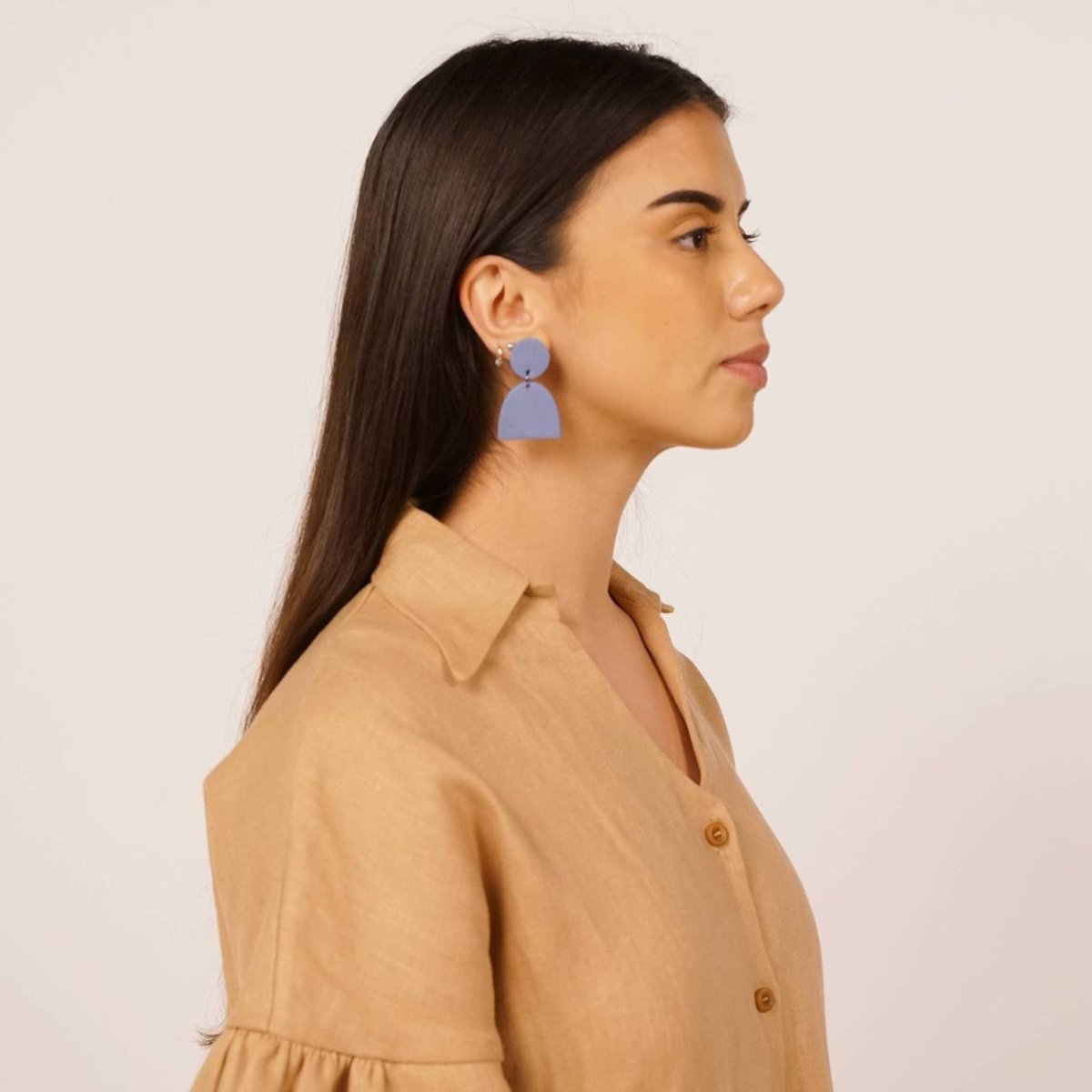 Aries earrings in the shade sky. Flat circle top piece joined by a a separate half-moon shaped bottom piece. Displayed on a model with dark brown hair. Made in Los Angeles, California by Hey Moon Designs.