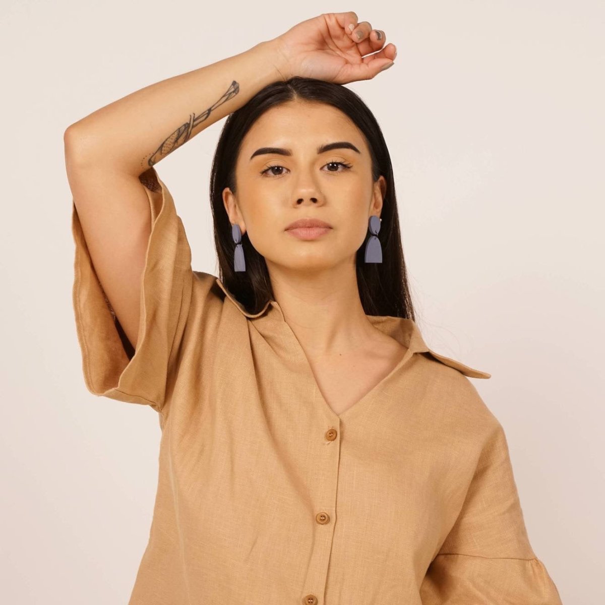 Aries earrings in the shade sky. Flat circle top piece joined by a a separate half-moon shaped bottom piece. Displayed on a model with dark brown hair. Made in Los Angeles, California by Hey Moon Designs.