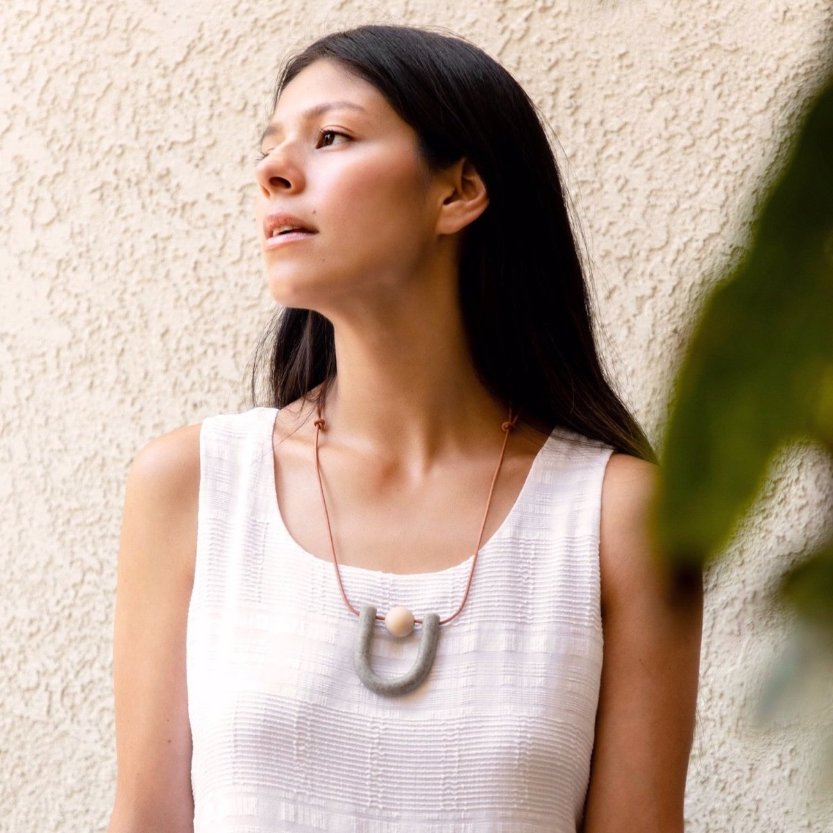 U-shaped focal piece made of polymer clay with a natural wood ball suspended by orange leather cord. Made by Hey Moon Designs in Los Angeles, CA. 