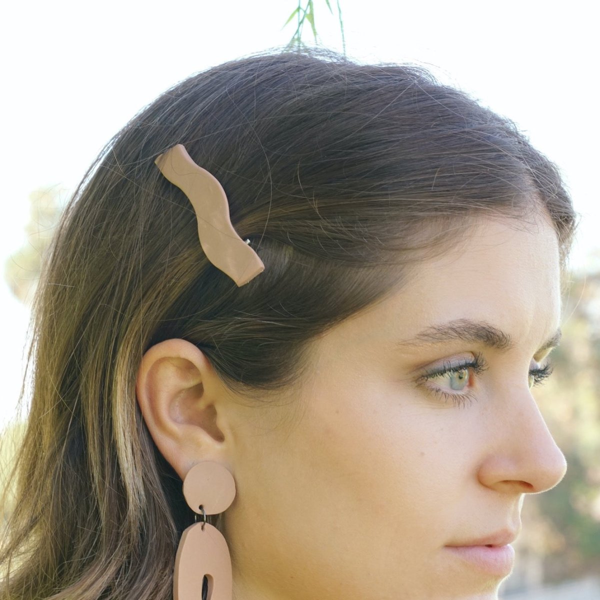 Wave shaped hair clip in the shade Desert. Hair clip is displayed on a model with light brown hair. Made in Los Angeles, California by Hey Moon Designs.