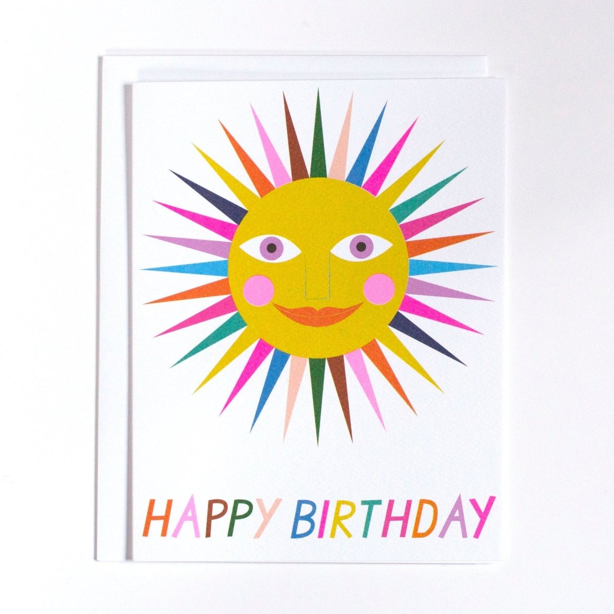 White card shows image of a multicolored smiling sun. Card reads: "Happy Birthday." Made with recycled paper by Banquet Atelier in Vancouver, British Columbia, Canada.