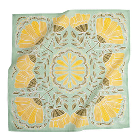 Light blue bandana with a mirror image of a yellow and green floral pattern and circular yellow petal pattern in center. Designed by Hemlock Goods Fulton, MO and screen printed by hand in India.