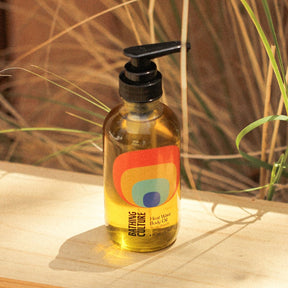 A clear bottle with a black pump top holds a body oil. The Heat Wave Body Oil is handcrafted by Bathing Culture in San Francisco, California.