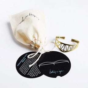 The brass betsy & iya Hernando de Soto Bridge cuff bracelet, accompanied by a betsy & iya muslin cuff bag and informational cards about the bridge and cuff care. Hand-crafted in Portland, Oregon.