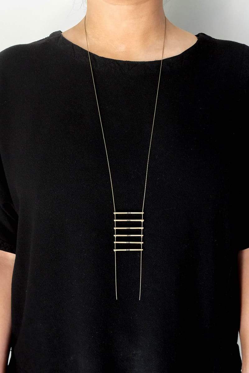 Long, cast-bronze betsy & iya Jalisco necklace, shown on a model wearing a black tunic.