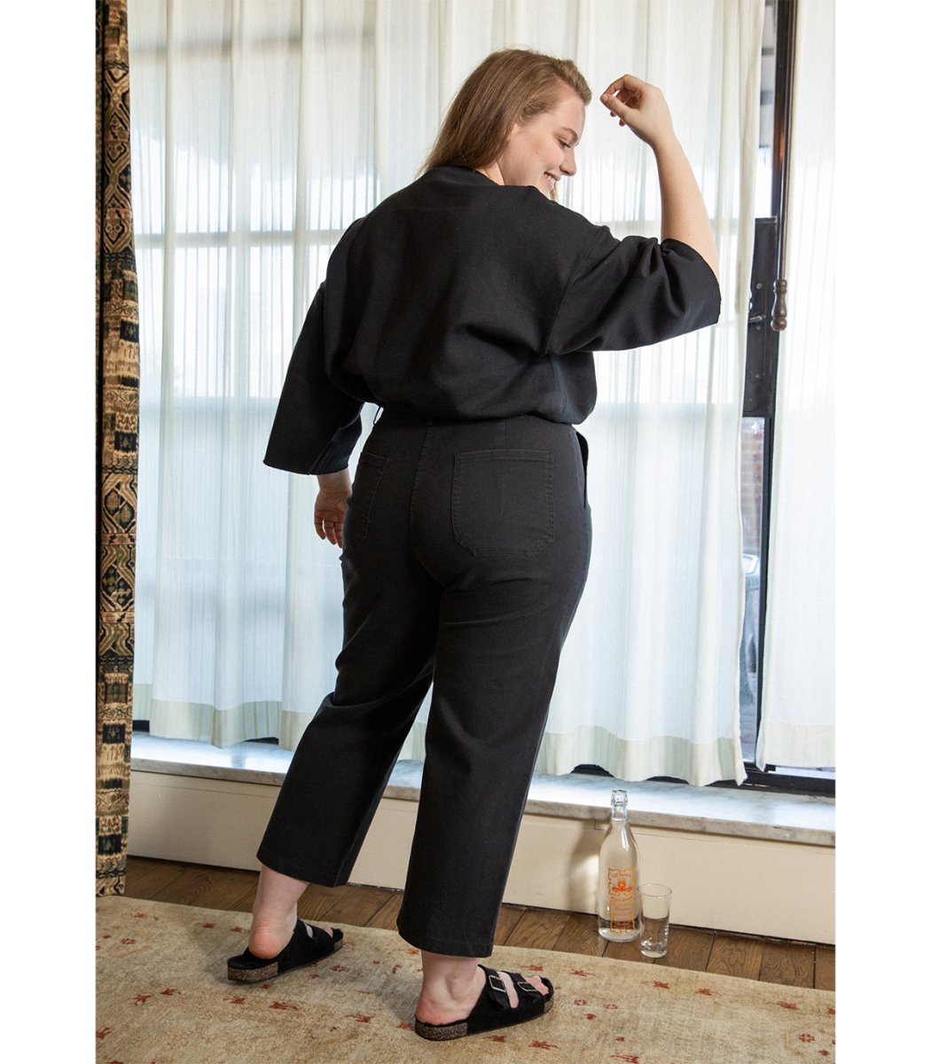 Model shows the back side of a straight leg cropped work pant in black. The James Pant in Black is designed by Loup and made in New York City, USA.