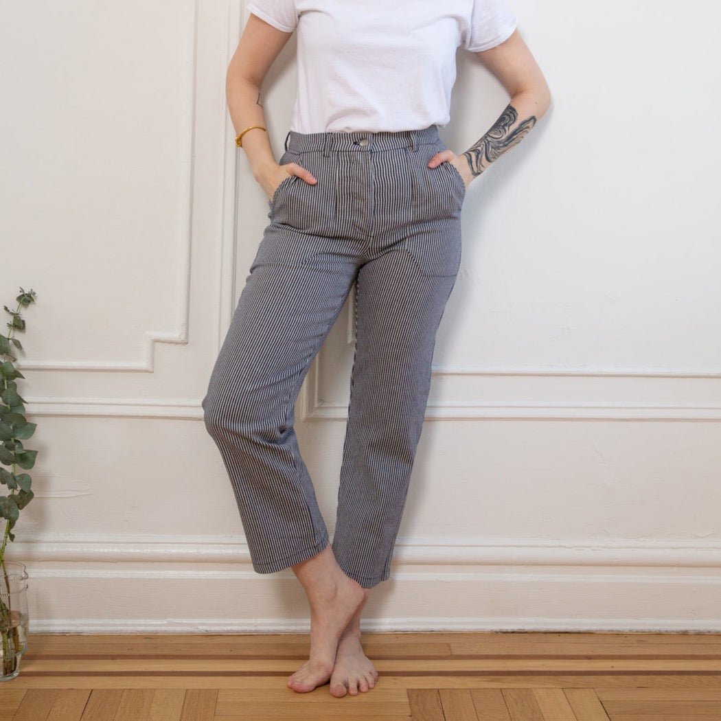 Model wears a straight leg work pant with a thin blue/grey striped pattern. The James Pant in Stripe is designed by Loup and made in New York City, USA.