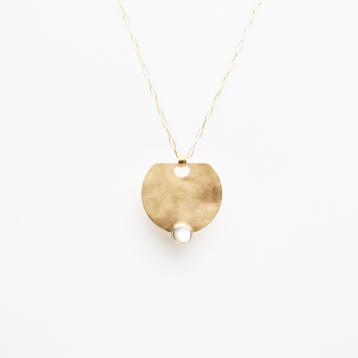 Rounded brass pendant necklace with a Mother of Pearl gemstone set at the bottom. Necklace hangs on a 14k gold filled chain. Designed by Kari Phillips in Portland, Oregon.