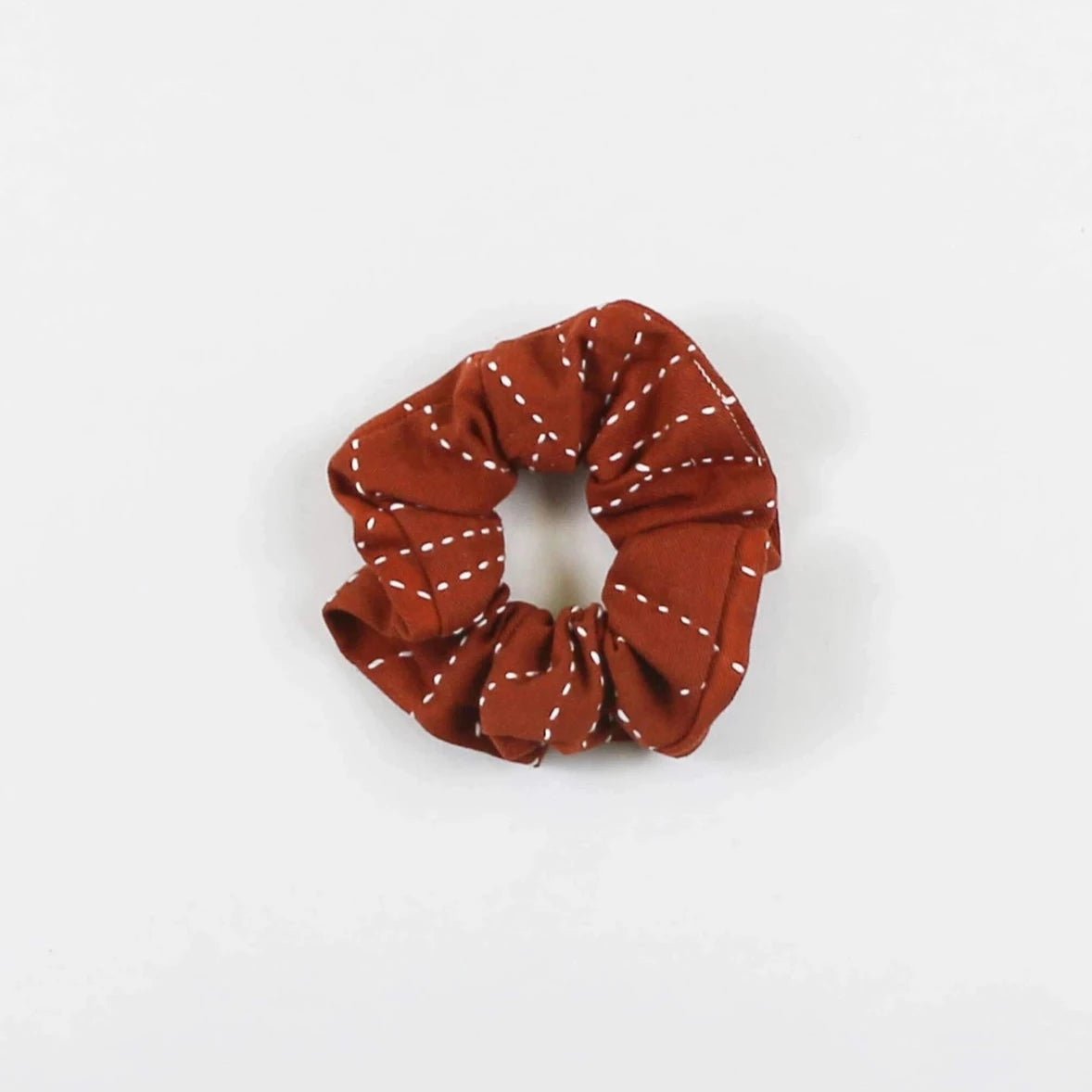Red cotton canvas scrunch with white stitching. The Kantha Scrunchie in Rust is designed by Anchal in Louisville, Kentucky and handmade in Ajmer, India.