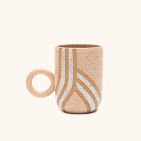 A tall and narrow mug with a circular handle in pink and white with a raw speckled clay design. The Circle Handle Mug in Pink & White is designed and handmade by Kohai Ceramics in Portland, OR.