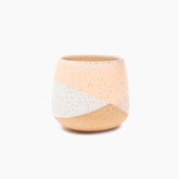 A peach and white colored handleless tea cup with a natural clay bottom. The Peach Dipped Tea Cup is designed and handmade by Kohai Ceramics in Portland, OR.